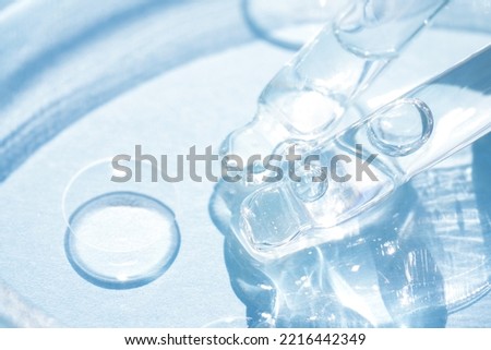 Pipettes with transparent cosmetic liquid or face serum over blue background. Texture of  hydrolate or cosmetic oil, beaty treatments. Selective focus
