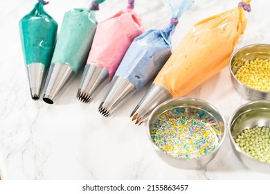 Piping bag with metal tips filled with colorful Italian buttercream frosting.