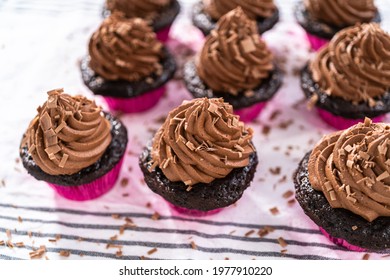 Piping Chocolate Ganache Frosting On Top Of Chocolate Cupcakes.