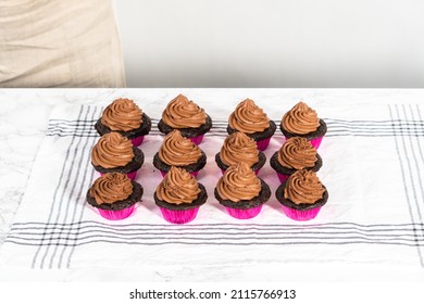 Piping Chocolate Ganache Frosting On Top Of Chocolate Cupcakes.