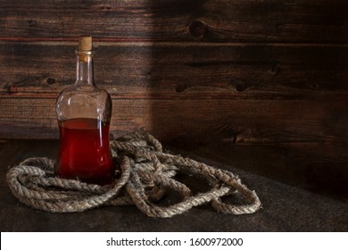 Pirate Bottle On The Table, Old Rope, Rum Or Whiskey In A Transparent Bottle, Wooden Background