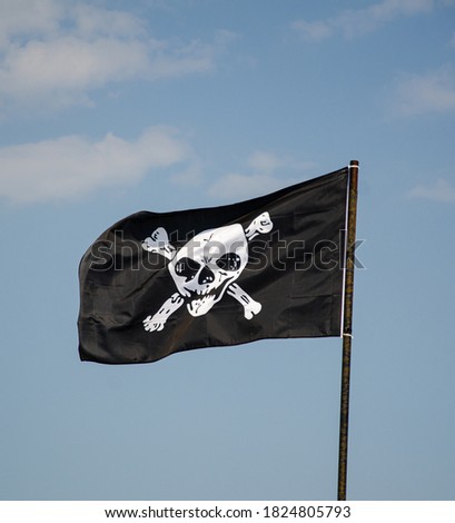 Pirate flag against the blue sky, skull and bones, jolly roger.