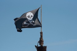 A Pirate Flag Is Displayed Against A Blue Sky.