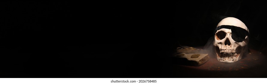 Pirate skull and treasure on dark background with space for text