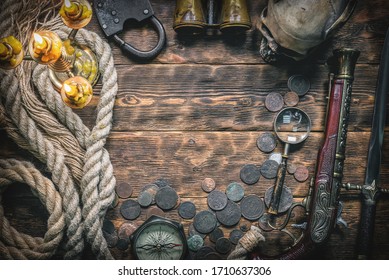 Pirate treasure chest with ancient coins and other various pirate equipment on flat lay table background.