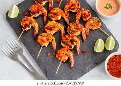 Piri Piri Grilled Shrimp On The Skewers With Lemon And Condiment On A Platter Directly Above Photo