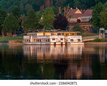 PIRNA, GERMANY - 18. May 2022: Boats on the Elbe river are waiting. The boat ride on the water is a famous tourist attraction. The sunset light is shining on the ships and the water is reflecting them