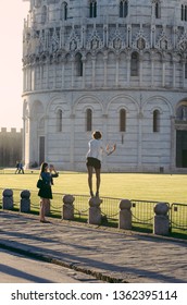 Pisa, Italy - 14 APRIL 2013: Tourist Try With Hands Out As If Hold Up And Brace The Leaning Tower Of Pisa On A Forced Perspective Shot On A Summer Day