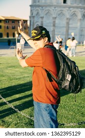 Pisa, Italy - 14 APRIL 2013: Tourist Try With Hands Out As If Hold Up And Brace The Leaning Tower Of Pisa On A Forced Perspective Shot On A Summer Day