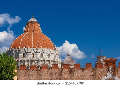 Pisa most famous three landmarks: Leaning Tower, Baptistry and Cathedral domes, seen from outiside the city ancient walls, with blue sky and white clouds