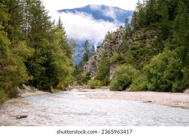 Pisnica valley in Triglav National Park, Kranjska Gora, Slovenia. Scenic landscape with river surrounded by wooded cliffs and misty Alps mountains, outdoor travel background