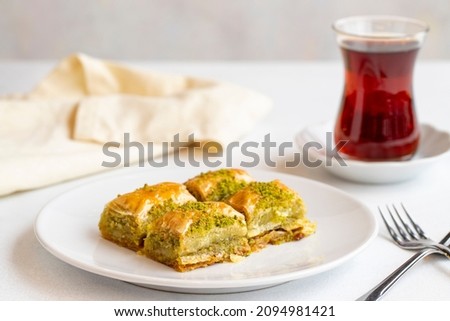 Pistachio baklava dessert on a white background. Turkish sweet dessert concept. plate of pistachio baklava. sherbet sweet Mediterranean bakery. close up. Horizontal view. Local name fistikli baklava