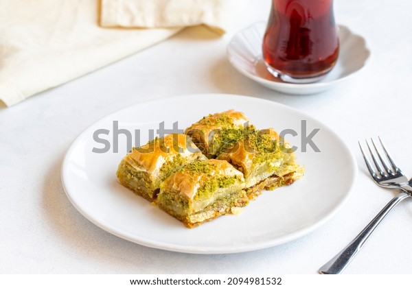 Pistachio baklava dessert on a white background.\
Turkish sweet dessert concept. plate of pistachio baklava. sherbet\
sweet Mediterranean bakery. close up. Horizontal view. Local name\
fistikli baklava