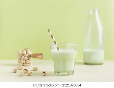 Pistachio milk the glass next to bottle of milk and pistachios