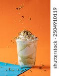 Pistachio milkshake on an orange background with a blue surface, combining vibrant colors and refreshing taste. Perfect for summer vibes, dessert drinks, and creative food photography projects