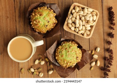 Pistachio Muffins Top View. Two Muffins With Coffee Mug. Wooden Background With Small Wooden Bowl With Whole Pistachio Nuts In Shells. 