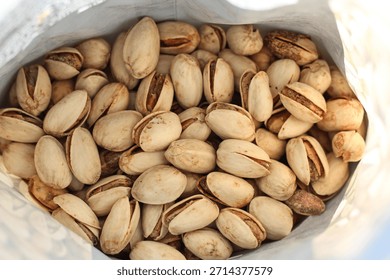Pistachio nuts in shell inside opened bag. Healthy snack concept, salted nuts texture, natural food background, close-up food photography