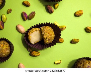 
Pistachio white chocolate truffle cut in two halves in a brown candy wrapper on a light green background. Pistachios and nutshells are scattered around. - Powered by Shutterstock