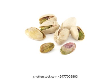 Pistachios are randomly spread across the white surface, some pistachios being in-shell and others peeled exposing the green nuts inside