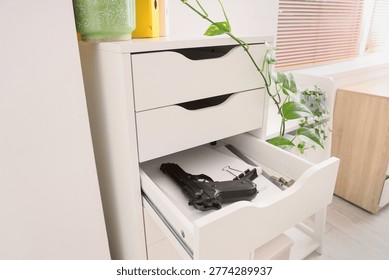 Pistol, bullets and documents in file drawer at office, closeup