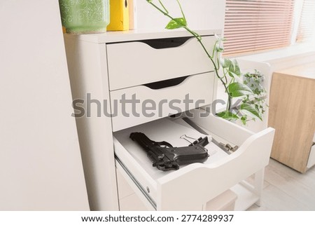 Pistol, bullets and documents in file drawer at office, closeup