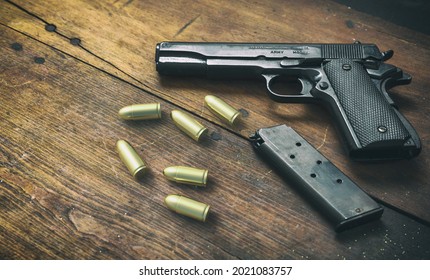 Pistol gun 9mm and ammo bullets on wooden background. Black metal weapon, automatic handgun for military and security on a vintage table. Side view