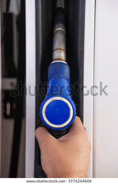 A pistol for refueling with\
gasoline at a gas station. A blue gas pump at a gas\
station.