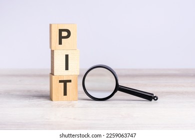 PIT - personal income tax - text wooden cube blocks and magnifying glass on table. business concept. - Shutterstock ID 2259063747