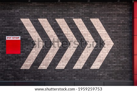 Pit stop direction indicators on a brick wall with a pit stop sign. Wall direction arrows.