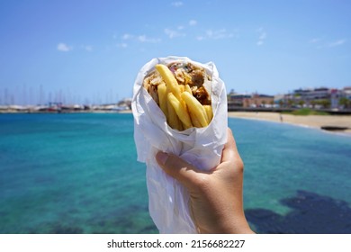 Pita Gyros. Greek gyros wrapped in pita breads against Greek beach with blue sea.