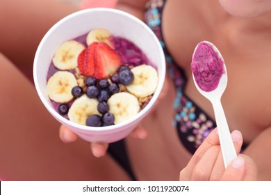 Pitaya Dragonfruit Breakfast Or Acai Bowl Smoothie. Girl Eating Food With Spoon On Beach. Cafe Or Restaurant Tropical Dessert.