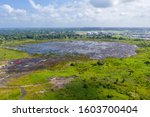 Pitch Lake, the liquid asphalt lake, the largest natural deposit of bitumen in the world.  La Brea, Trinidad island, Trinidad and Tobago. Natural asphalt mining and industrial trains of red minecarts.