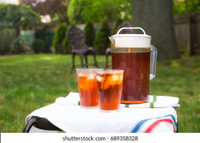 Pitcher of iced tea and two glasses in outdoor backyard summer setting