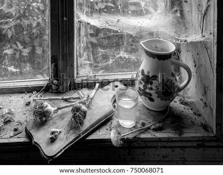 Pitcher on the windowsill with cobweb of rustic window. Selective focus