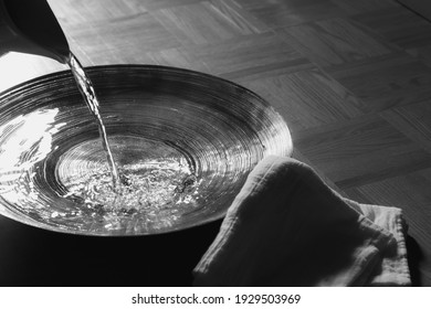 Pitcher pouring water into basin with linen cloth
