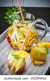 A pitcher of white peach sangria with two glasses