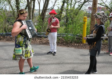 Pittsburgh, PA USA. April 30, 2022. Young woman playing the accordion and a young man playing the saxophone are seen entertaining a senior woman before the start of the May Day parade.