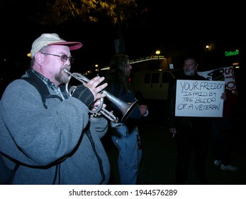 Pittsburgh, PA USA. October 23, 2011. Older Man Playing His Trumpet By Another Older Man Holding A Protest Sign About Veterans In Pittsburgh,PA.