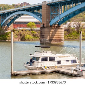 Pittsburgh, Pennsylvania, USA 5/10/20 A House Boat Moored To A Wooden Dock On The Allegheny River Under A Bridge On A Sunny Spring Day