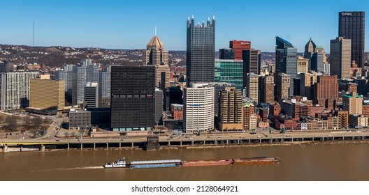 Pittsburgh, Pennsylvania, USA February 20, 2022 A tow boat pushing four barges up a muddy Monongahela River next to downtown Pittsburgh on a sunny winter day