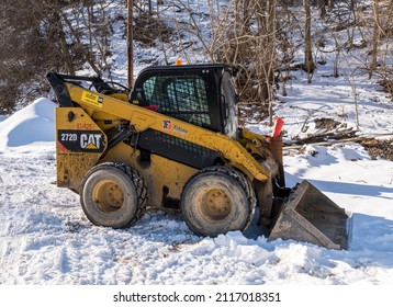 Pittsburgh, Pennsylvania, USA January 29, 2022 A Peterson Cat 272D Skid Steer Loader parked in the snow in Frick Park on a sunny winter day