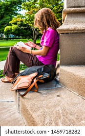 Pittsburgh, Pennsylvania, USA, woman engrossed in her book on the steps of Heinz Memorial Chapel, University of Pittsburgh, July 23, 2013