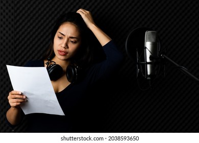 Pity Asian Woman Singer Exhausted With Note Paper In Hand, Feel Stressed On Singing, Worry Of Mistake Acoustic, Disappointed On Voice And Sound Record In Dark Room Of Music Studio.