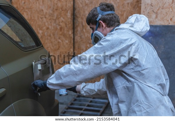 Pixel car\
painting. A man in a respirator paints a car. Painting in\
camouflage. DNIPRO, UKRAINE - April 29,\
2022