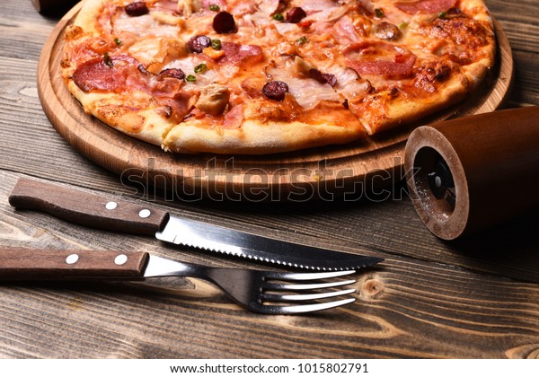 木の背景にピザとベーコンとチーズ 接写 ファストフードのコンセプト イタリア料理のフォーク ナイフ コショウ用のミル イタリアンレストラン カフェ ピザ屋で食事をする の写真素材 今すぐ編集