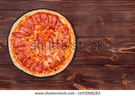 Pizza bacon on slate bottom, on wooden table, top view, space for text