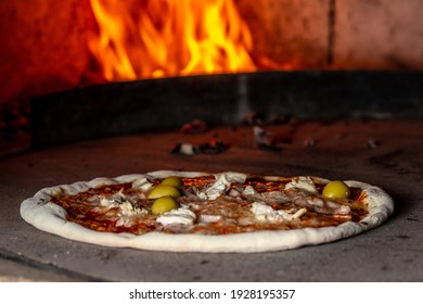 Pizza baking close up in the oven. Italian pizza is cooked in a wood-fired oven. Traditional baked wood fired oven.
