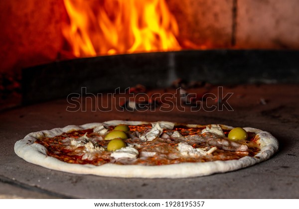 Pizza\
baking close up in the oven. Italian pizza is cooked in a\
wood-fired oven. Traditional baked wood fired\
oven.