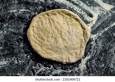 Pizza Base From Dough On A Dark Table Top View.