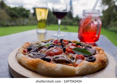 pizza, beer, soda and a glass of wine at the green garden in a gray day - Powered by Shutterstock